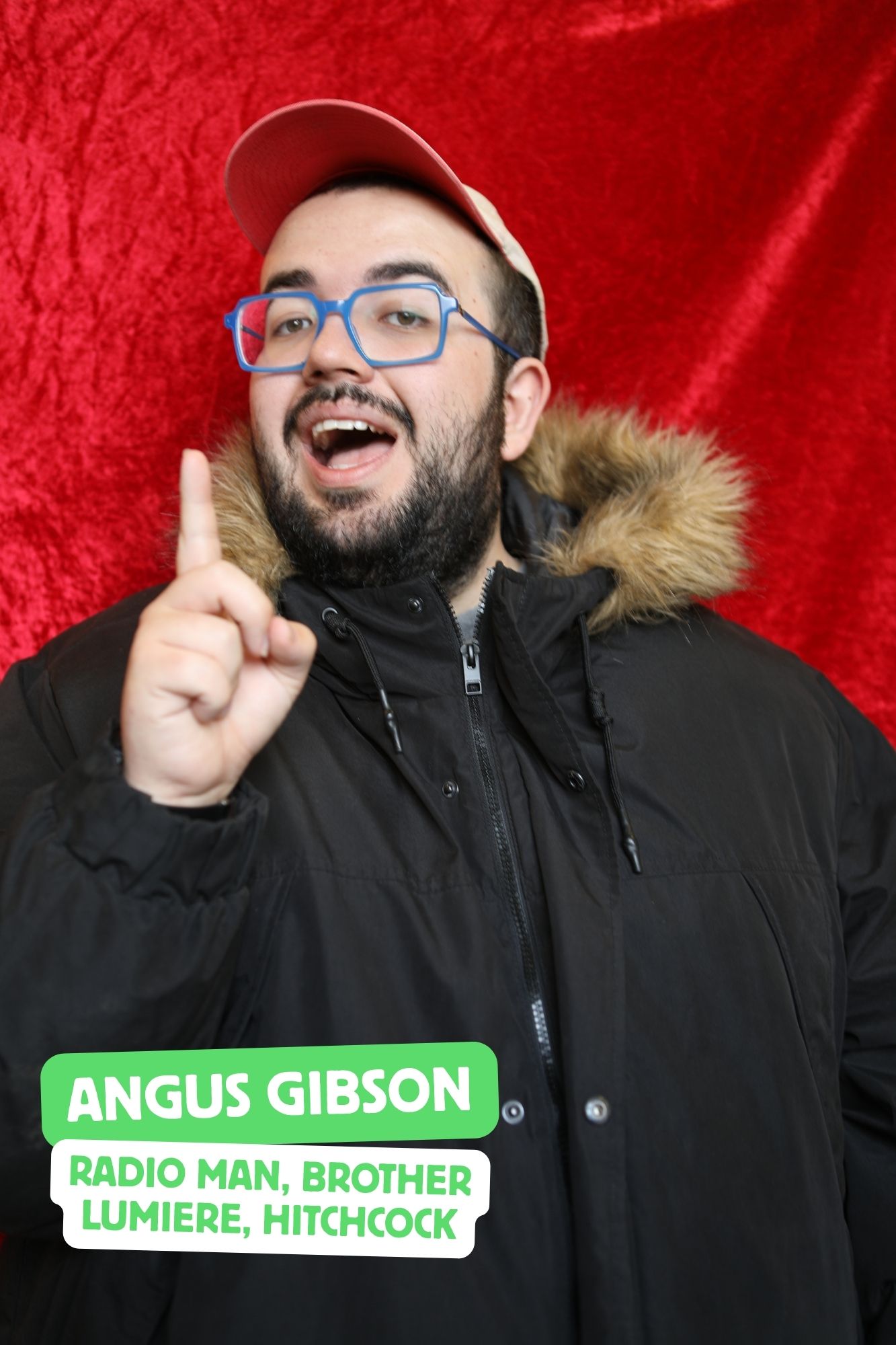 Angus, a white man with a short, black beard, is playing Craig Castaldo. He is wearing a large black coat, with a hat and scarf.