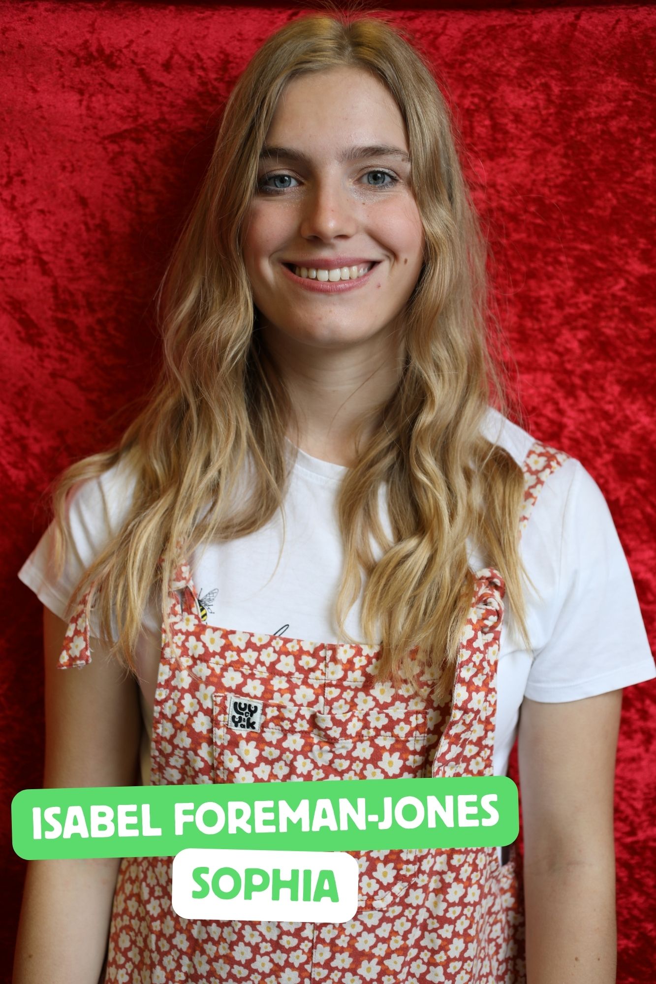 Isabel, a tall, white woman with long, blonde hair and a big smile is playing Sophia. She is wearing floral dungarees.