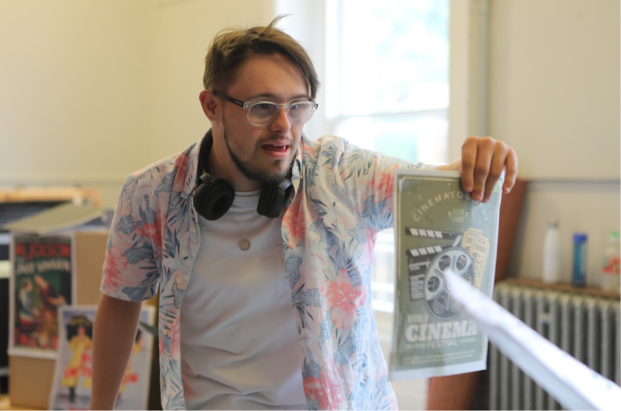 Jamie at rehearsals, holds a leaflet up to another character.