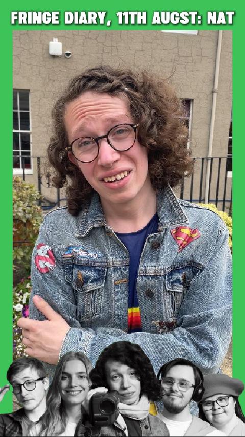 Nat, a white transwoman with brown curly hair is wearing classes and a denim jacket covered in movie-themed patches.